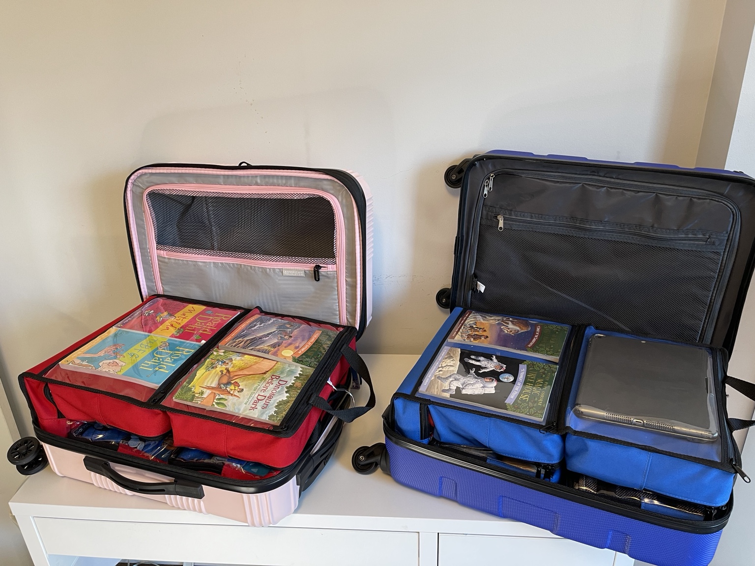 Pink and blue SuitcaseMates packed inside two open carry-on suitcases
